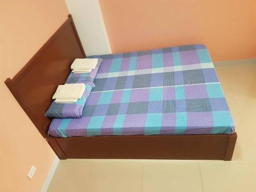 a bed with a plaid mattress and three pillows at Mayon Lodging House in Legazpi