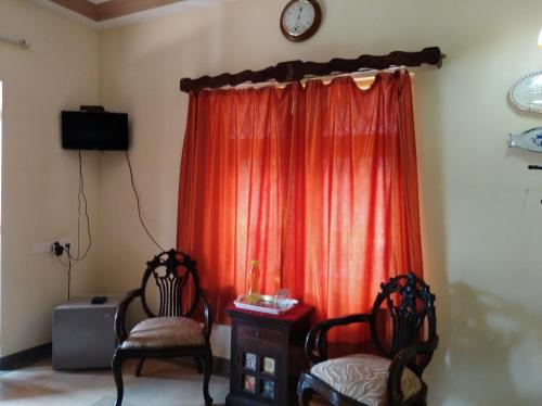 a room with two chairs and a red curtain at The Pereira's Goan Homestay Villa in Vasco Da Gama