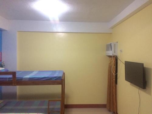 a room with a bed and a tv and a wall at Mayon Lodging House in Legazpi