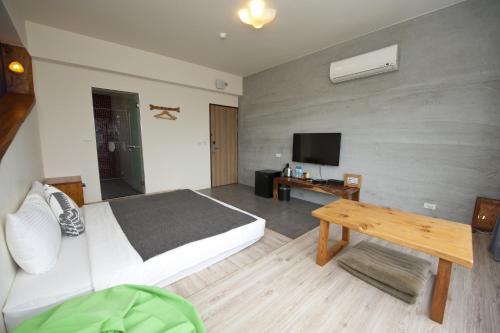 a bedroom with a bed and a table and a tv at 有棵樹特色民宿The Tree in Hengchun