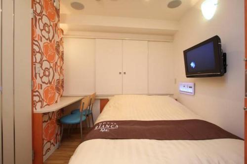 ein Schlafzimmer mit einem Bett und einem TV an der Wand in der Unterkunft Hotel Bianca Due (Adult Only) in Tokio