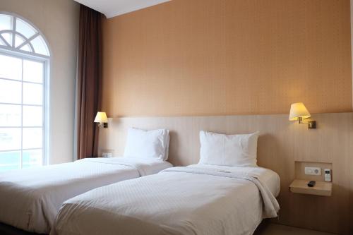 two beds in a hotel room with a window at Rio City Hotel in Palembang