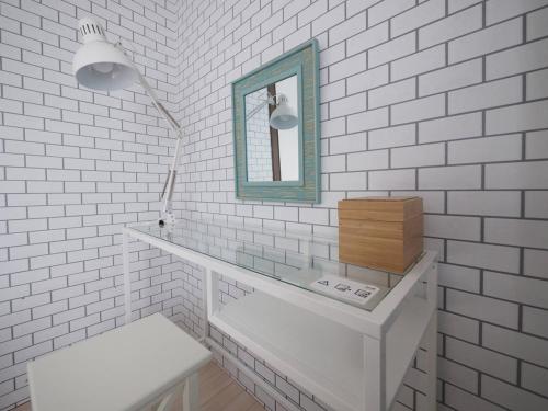 a white bathroom with a mirror and a white brick wall at Comfort CUBE PHOENIX Beppu (やよいビル) in Beppu