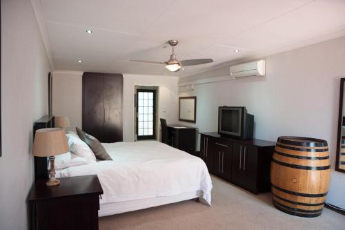 a bedroom with a bed and a tv and a barrel at The Lazy Grape Guest Lodge & Spa in Benoni