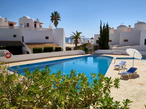 a swimming pool with two chairs and a villa at E&M Beach House Aldeamento do Levante II in Lagoa