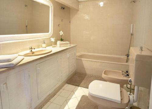 a bathroom with a sink and a toilet and a tub at E&M Beach House Aldeamento do Levante II in Lagoa