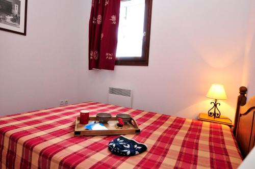 ein Schlafzimmer mit einem Bett mit einer karierten Decke in der Unterkunft Résidence Goélia Les Terrasses du Corbier in Le Corbier