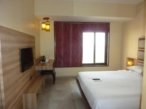 a hotel room with a bed and a window at Hotel New Bengal in Mumbai