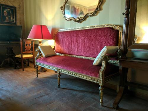 a red couch in a room with a lamp and a mirror at Al Tuscany in Lucca