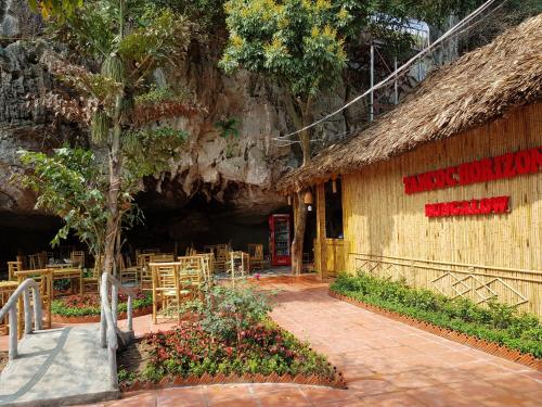 a restaurant with tables and chairs in front of a cave at Tam Coc Horizon Bungalow in Ninh Binh