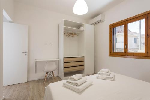 a white bedroom with two white towels on a bed at BOBO' in Marina di Ragusa