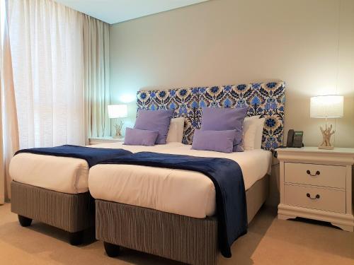 Zimbali Suite 311 في باليتو: غرفة نوم مع سرير كبير مع وسائد أرجوانية
