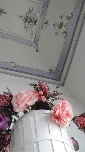 a white vase with pink flowers and a mirror at Affittacamere Museo in Taranto