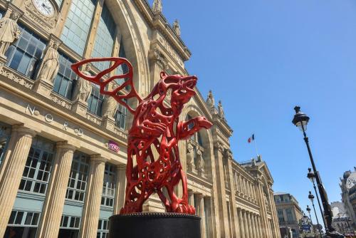 a red sculpture of a dog in front of a building at Hôtel Paris Nord in Paris