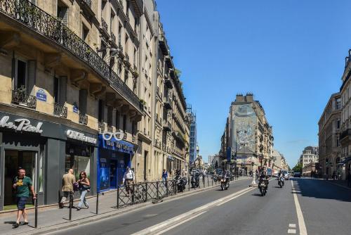 people riding motorcycles down a city street with buildings at Hôtel Paris Nord in Paris