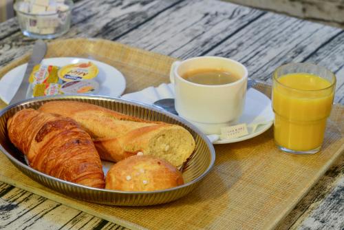 a tray with bread and a cup of coffee and orange juice at Hôtel Paris Nord in Paris