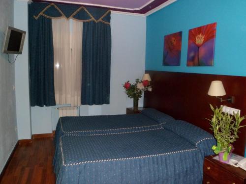 1 dormitorio con 1 cama azul y paredes azules en Auto Check In Hotel Las Nieves, en Jaca