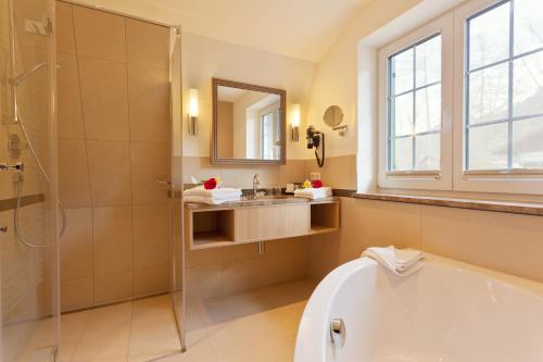 a bathroom with a tub and a shower and a sink at Villa Ludwig Suite Hotel in Hohenschwangau