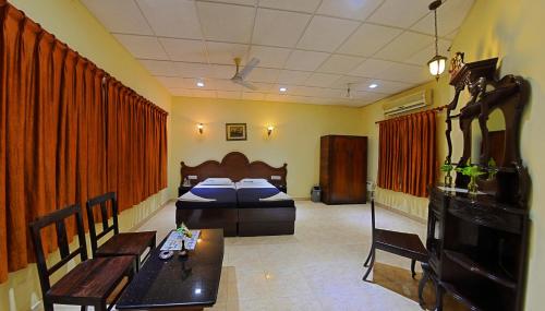 a room with two beds and a table and a couch at Hotel Mahabs in Mahabalipuram