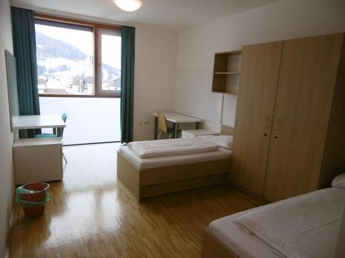 a room with two beds and a desk and a window at Jugendherberge Tamsweg in Tamsweg