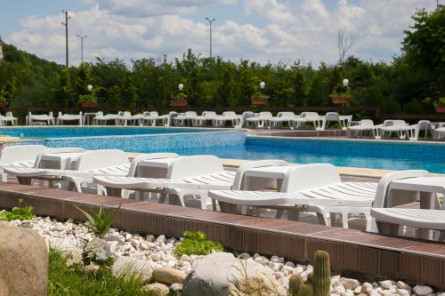 a pool with white lounge chairs next to a swimming pool at Complex Perpera in Stambolovo