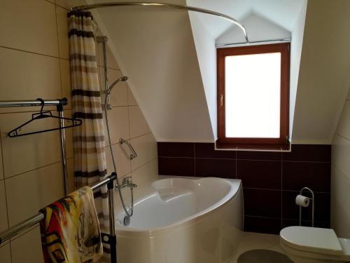ザラツァニにあるVillapark Z/4 appartmanのバスルーム(バスタブ、トイレ付)、窓が備わります。