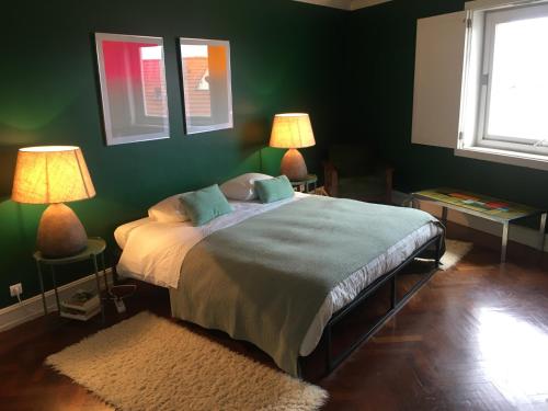 リスボンにあるChiado Glamorous Design Apartmentのベッドルーム1室(緑の壁のベッド1台、ランプ2つ付)