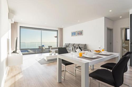 a dining room and living room with a white table and chairs at Searenity Vacation Home II by An Island Apart in Arco da Calheta