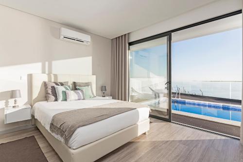 sypialnia z dużym łóżkiem i dużym oknem w obiekcie Searenity Vacation Home II by An Island Apart w mieście Arco da Calheta