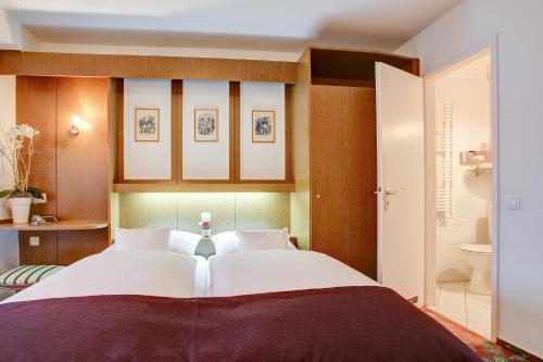 a bedroom with a large bed and a bathroom at Hotel Consul in Kiel