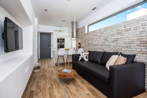 uma sala de estar com um sofá preto e uma parede de tijolos em Yianna's Flat em Faliraki