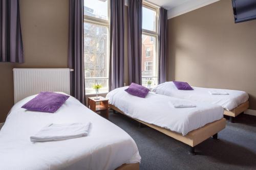 two beds in a hotel room with purple pillows at Hotel Santa Maria in Rotterdam