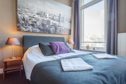 a bedroom with a blue bed with a large window at Hotel Santa Maria in Rotterdam