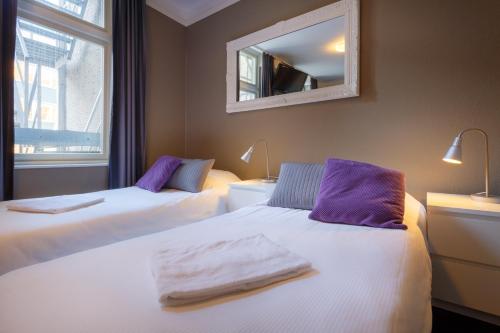 two beds in a room with a mirror on the wall at Hotel Santa Maria in Rotterdam