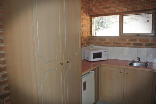 a kitchen with a door with a microwave and a sink at Eltham Motor Inn in Eltham