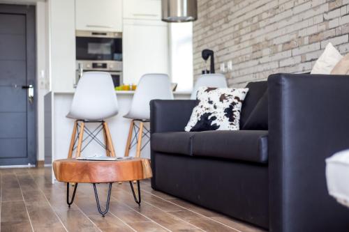 a living room with a black couch and two white stools at Yianna's Flat in Faliraki