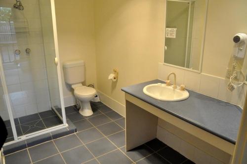 a bathroom with a toilet, sink, and mirror at West City Motel in Ardeer