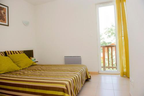 - une chambre dotée d'un lit avec une couverture jaune et blanche dans l'établissement Les Maisons du Golf d'Armagnac, à Eauze