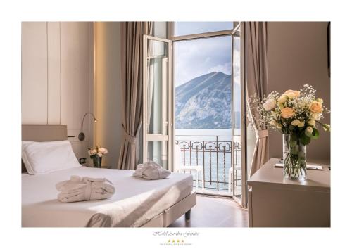 a hotel room with two beds and a vase of flowers at Araba Fenice Hotel in Iseo