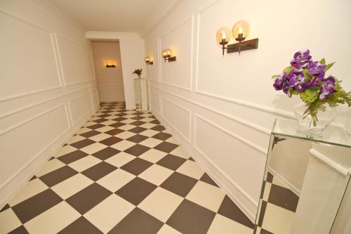 a hallway with a checkered floor and a vase of purple flowers at Tbilisi View Hotel in Tbilisi City