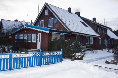 una casa roja con una cerca azul en la nieve en Skruzdynės Apartamentai, en Nida