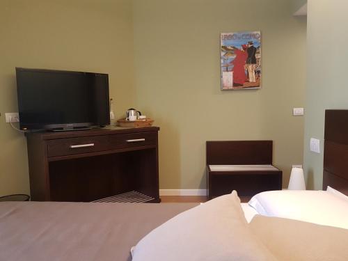 a bedroom with a tv on a dresser with a bed at Foresteria Lombarda La Spiaggia in Lierna