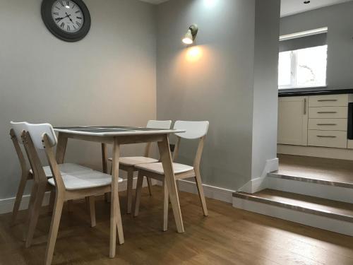 a dining room table with chairs and a clock on the wall at The Cothi Bridge Apartments in Carmarthen