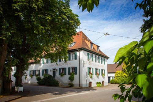 a white building with a red roof on a street at Storchen Restaurant Hotel in Bad Krozingen