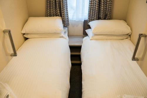 two beds in a small room with a window at Newby Bridge Country Caravan Park in Newby Bridge