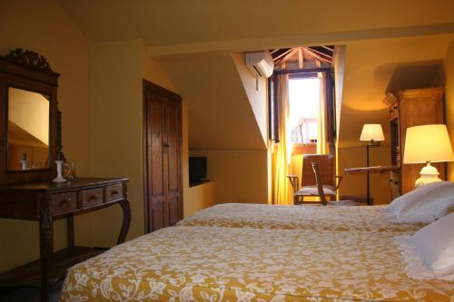 a bedroom with a bed and a desk and a window at La Posada de Don Mariano in Pedraza-Segovia