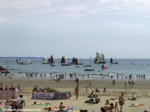 a group of people on a beach with boats in the water at Sand Martin in Looe