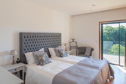 two beds in a white bedroom with a window at Quinta do Fontelo in Vouzela