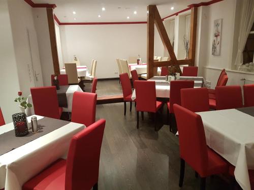 a dining room with tables and red chairs at Ratskeller Nörten in Nörten-Hardenberg