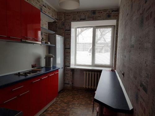 eine Küche mit roten Schränken und einem Fenster in der Unterkunft Hostel 888 У Вокзала in Nowosibirsk